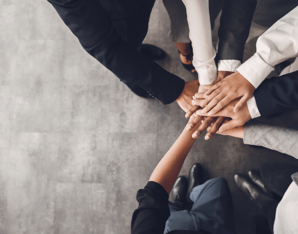 A team of business professionals, stacking their hands on one another